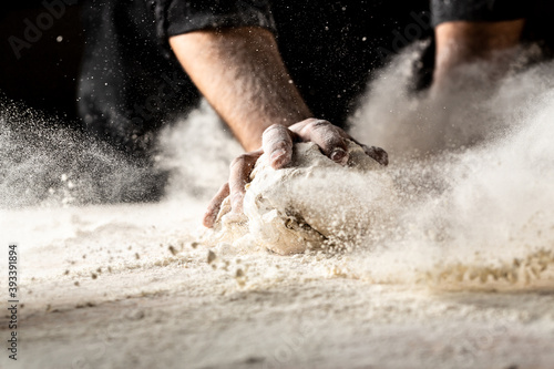 Powdery flour flying into air. chef hands with flour in a freeze motion of a cloud of flour midair. Hands kneading raw dough. Culinary, cooking, bakery concept