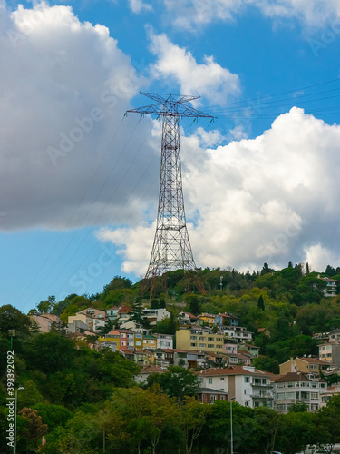 Electric power line post and high-voltage lines above houses on hill in Istanbul, Turkey