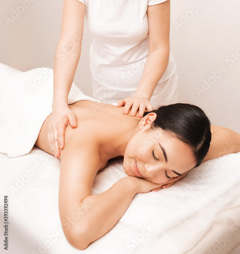 Thai massage. Asian woman with closed eyes in pleasure during massage in spa salon