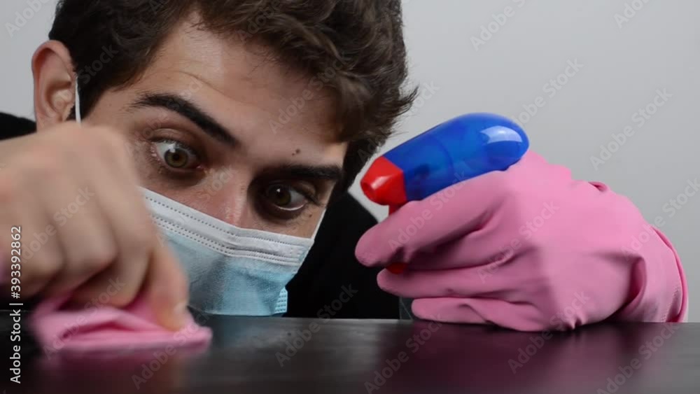 chico joven con mascarilla sanitaria limpiando mesa como un loco