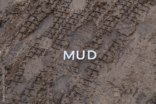 the word mud laid with silver metal letters on wet dirt surface photo