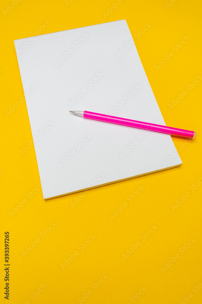 Notepad with copy space with pink pen on yellow background.Simple bright background with place for text Notepad with copy space with pink pen on yellow background.Simple bright background with place for text
