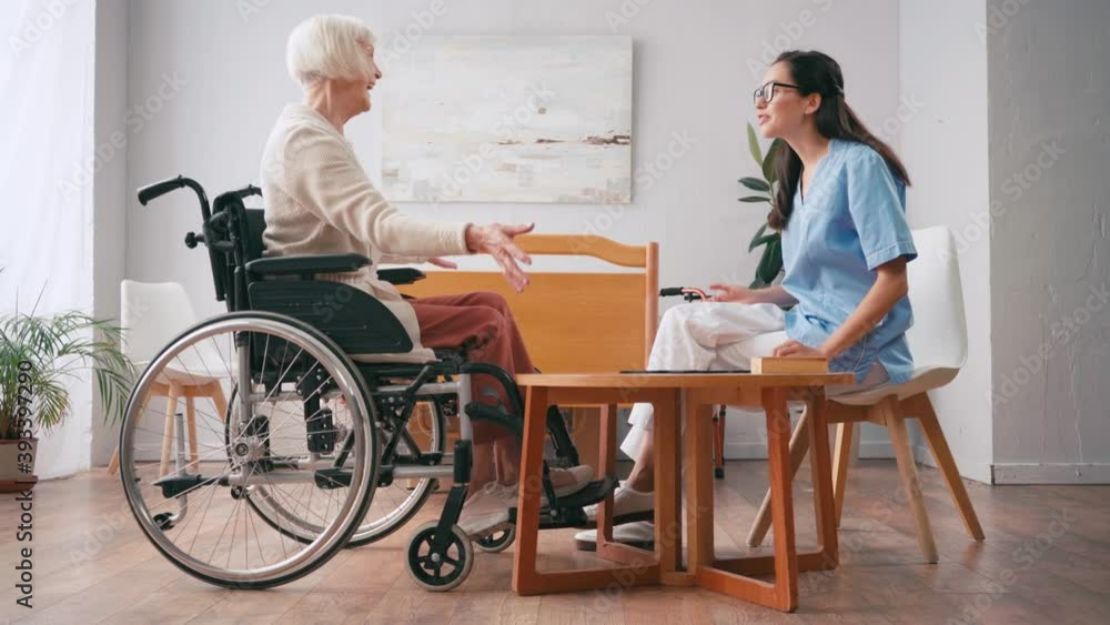 young nurse and senior woman shaking hands while playing board game young nurse and senior woman shaking hands while playing board game