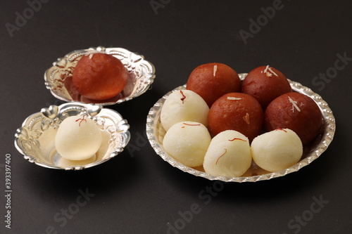 Famous Indian desserts rasgulla/ rosogulla/ roshogulla and gulab jamun/ gulabjam served in silver plate/ bowl. photo