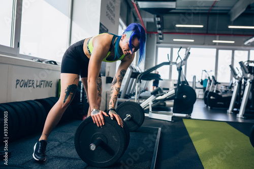 tattooed woman preparing for power lifting in gym