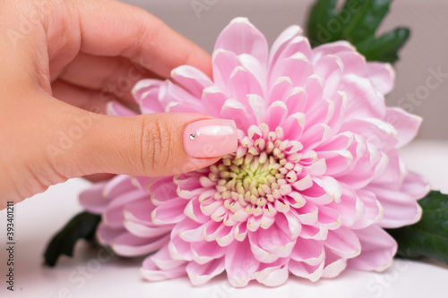 Female hand with wedding manicure nails, nude gel polish, peony flower