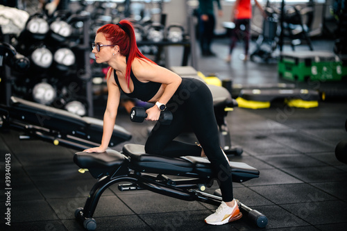 Athletic fit woman doing gym workout with dumbbells. Woman doing gym training with dumbbells