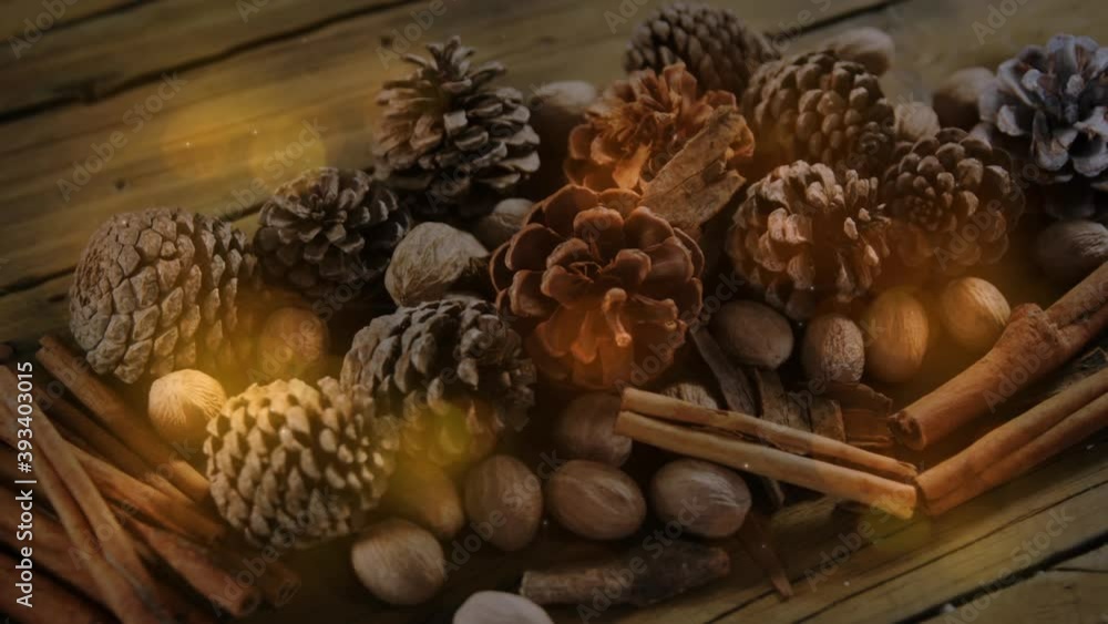 Digital composition of glowing golden spots of light moving against christmas pine cons and spices o Digital composition of glowing golden spots of light moving against christmas pine cons and spices o