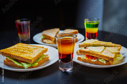 Club sandwiches & Mexican shots served for party in bar.Snack food and strong alcoholic drinks on table in night club photo