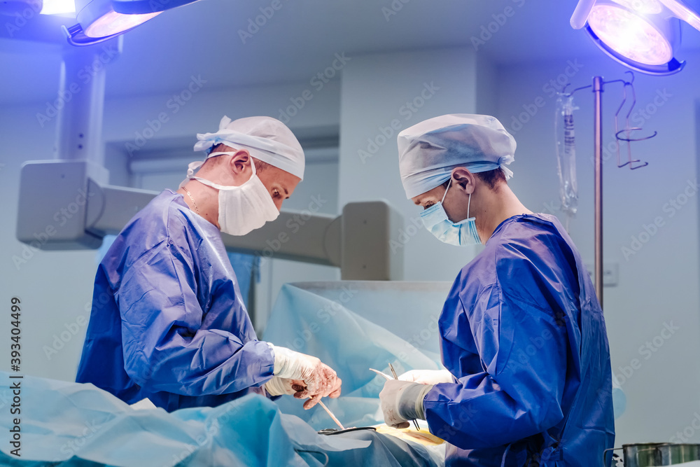 Neurosurgeons performing surgical operation in bright modern surgery room. Operating theatre. Modern equipment in clinic. Neurosurgeons performing surgical operation in bright modern surgery room. Operating theatre. Modern equipment in clinic.