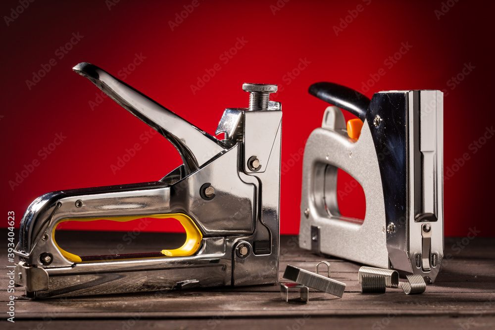 Two silver construction staples on a wooden table with staples, on a red background Two silver construction staples on a wooden table with staples, on a red background