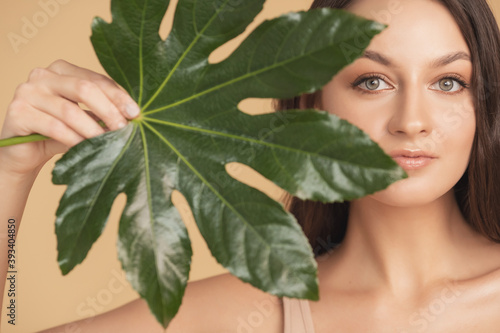 Portrait young beautiful woman with smooth skin in tropical leaves in studio. Concept skincare natural flora cosmetics