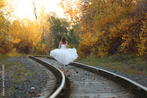 Runaway bride. Young girl running on railway in wedding dress. 