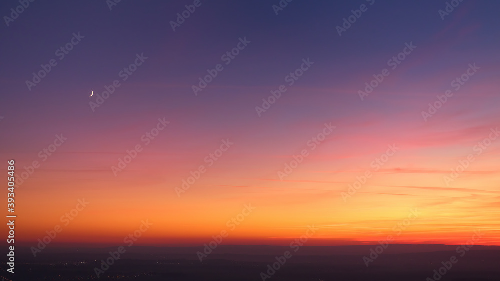 Evening colorful purple-pink sky with red clouds and orange horizon, crescent moon. Aerial photography, sky over the whole photo. Photos perfect for background exchange.