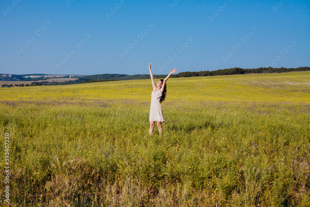 Portrait of a beautiful fashionable woman in a dress in a field with yellow flowers Portrait of a beautiful fashionable woman in a dress in a field with yellow flowers