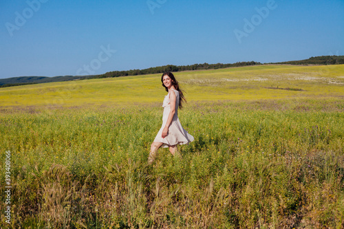 Portrait of a beautiful fashionable woman in a dress in a field with yellow flowers
