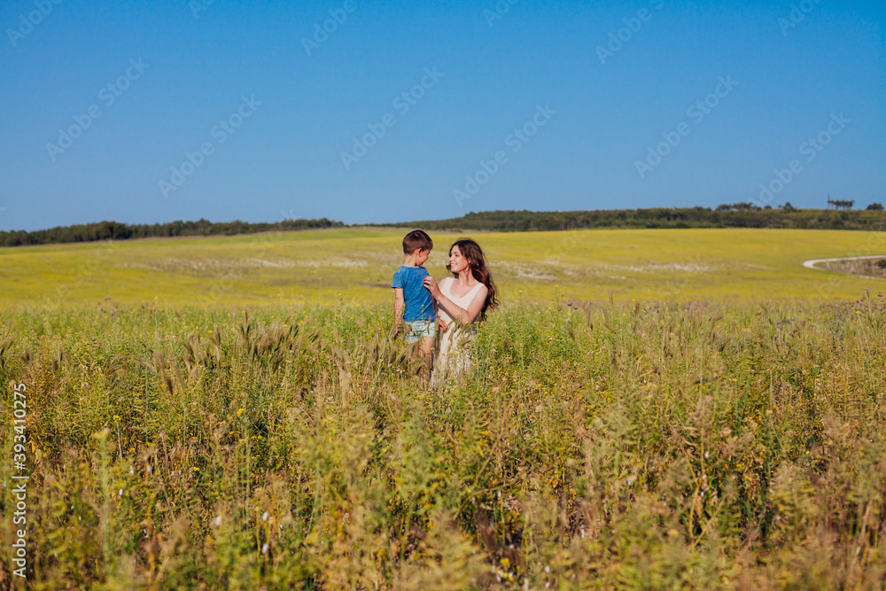 Beautiful woman mom hugs young son in nature on a walk