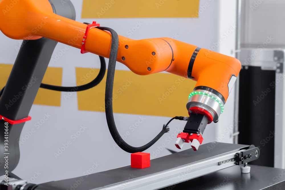 Orange pick and place robotic clamp arm manipulator moving red toy blocks  at modern robot trade show, exhibition. Manufacturing, engineering,  industrial, ai, automated technology concept foto de Stock | Adobe Stock