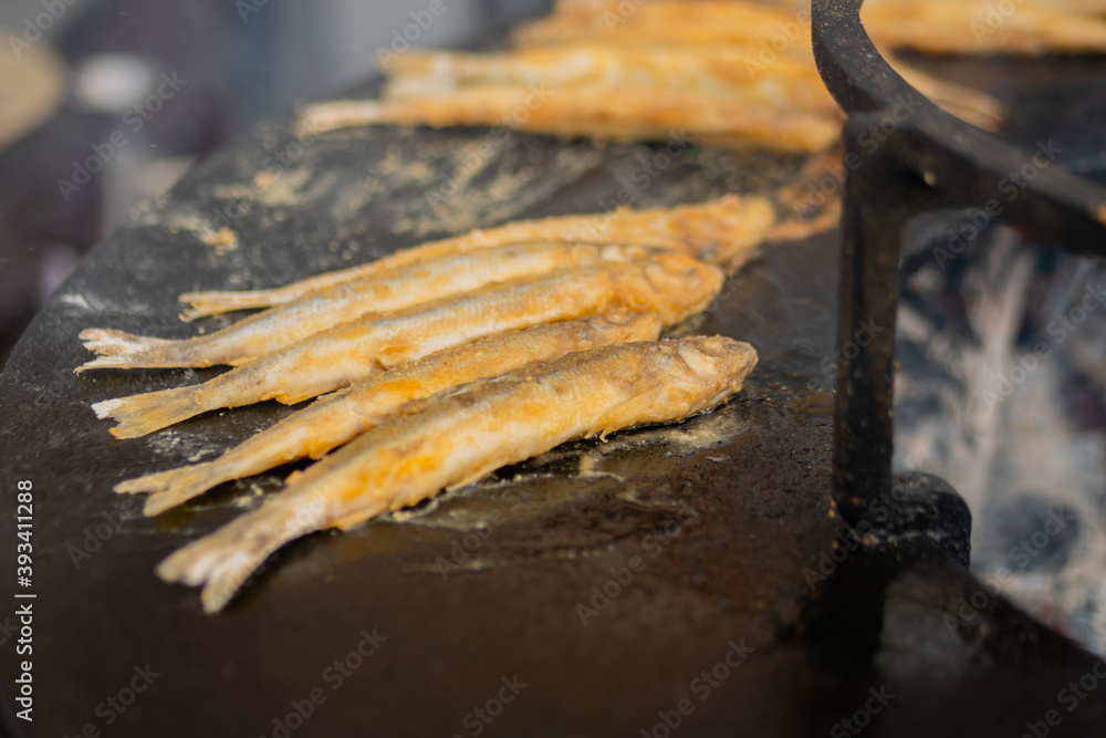 Process of cooking european smelt fish on black brazier at summer outdoor food market: close up. Seafood, barbecue, gastronomy, cookery, street food concept Process of cooking european smelt fish on black brazier at summer outdoor food market: close up. Seafood, barbecue, gastronomy, cookery, street food concept