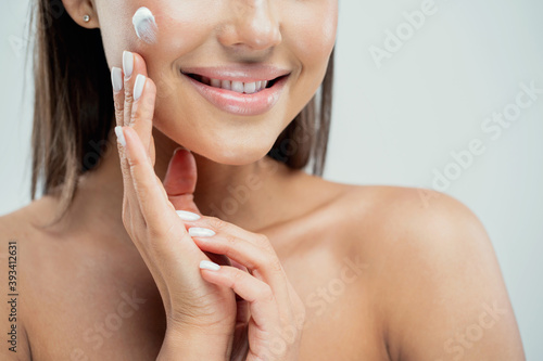apply face cream to clean skin. refreshing cleansing women's cosmetics. the woman smiles showing even white teeth