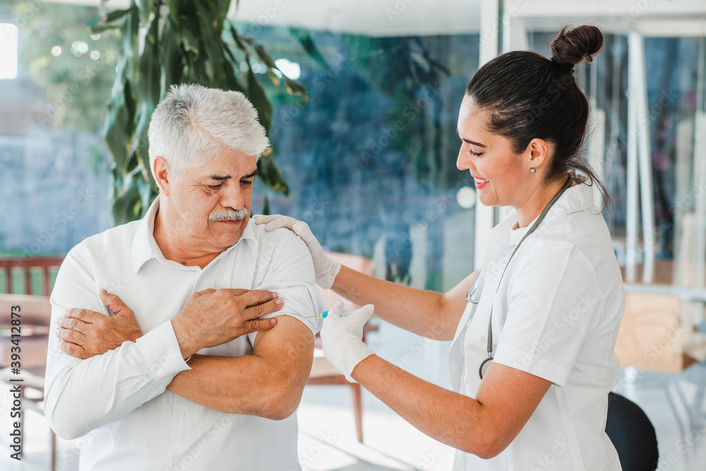 Obraz premium hispanic woman nurse injecting vaccine into senior patient's arm