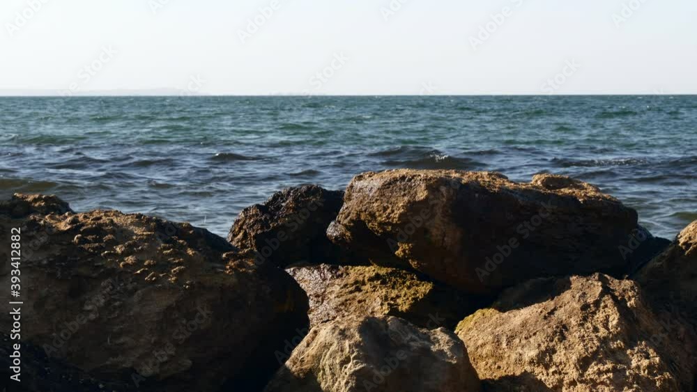 Front View Of Sea Waves Breaking On Rocks And Beach Boulders In Summer Day At Sunset. Front View Of Sea Waves Breaking On Rocks And Beach Boulders In Summer Day At Sunset.