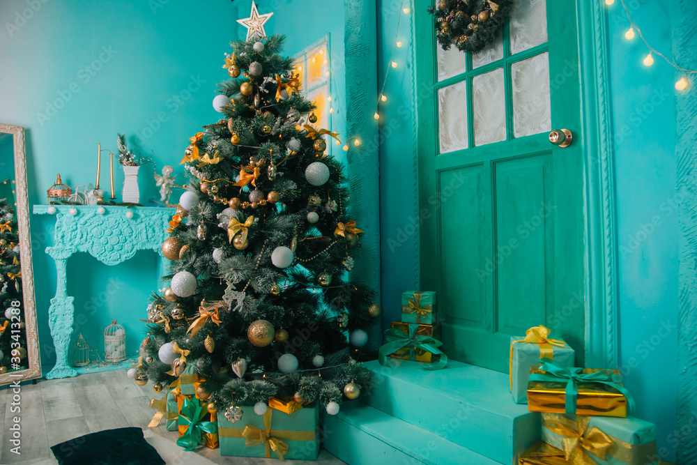 New Year's decor in the style of a New Year's card in gold and turquoise colors. A porch of a house, a green door with a wreath, a tree with gold and white balls. Gift boxes under the tree