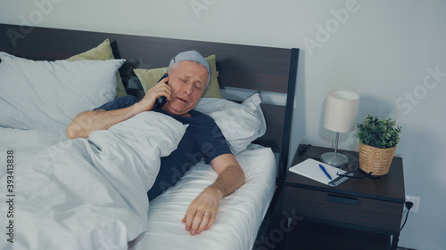 A man wakes up in bed and talks sleepily on the phone.
