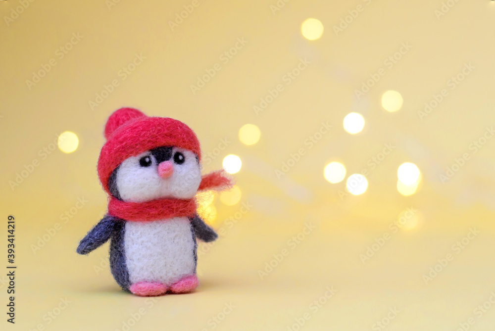 Toy wool penguin on a yellow background with bokeh