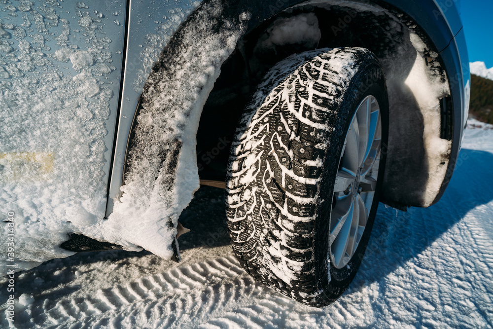 Winter tire. Car on snow road. Tires on snowy highway detail.