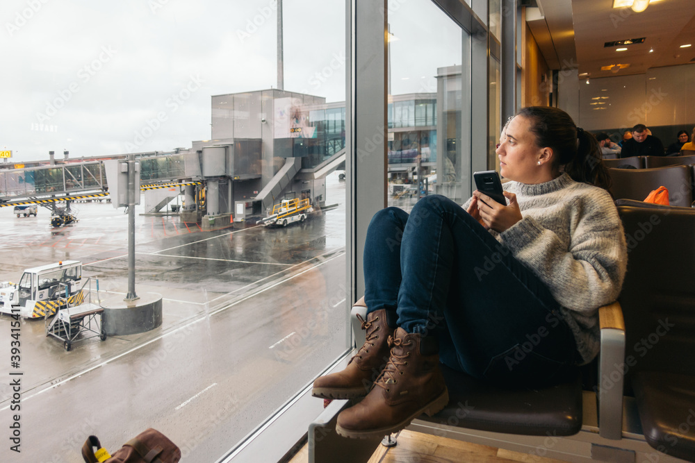 woman waiting at the airport using her smartphone woman waiting at the airport using her smartphone
