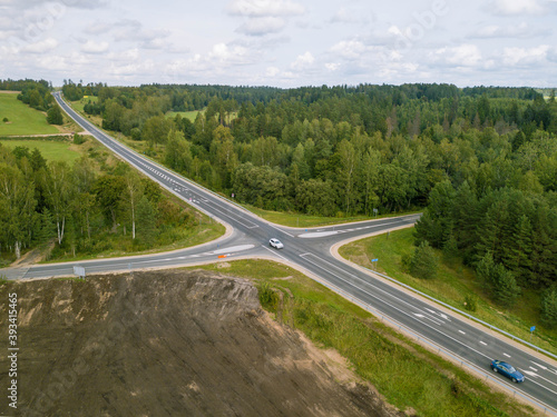 Aerial view from above of highway intersection, green forest and construction site.