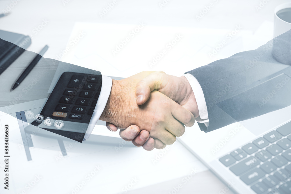 Double exposure handshake of two businessmen and calculator on the table on background, financial partnership concept Double exposure handshake of two businessmen and calculator on the table on background, financial partnership concept