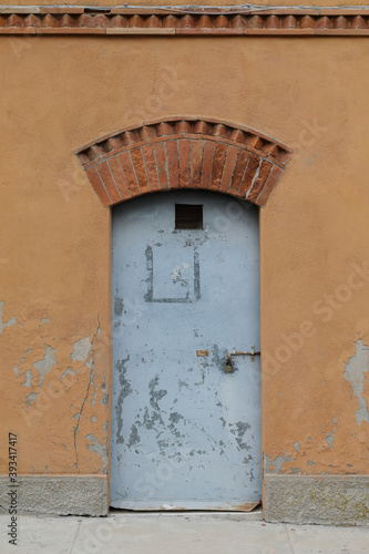Beautiful old house wall with ornaments, entrance door grey, weathered and damaged, space for text and perfect background, vertical format