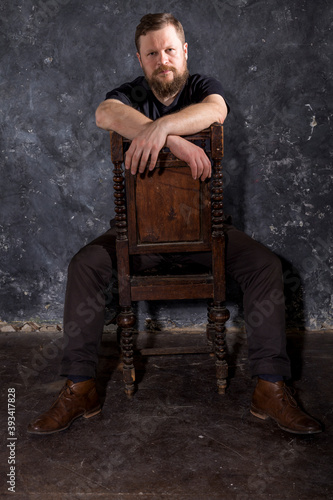 Mature bearded man dressed in t-shirt sitting on chair