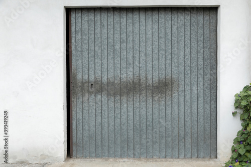 Bright building wall with  garage door with grey closed shutters, metal gate blank with space for text, perfect background