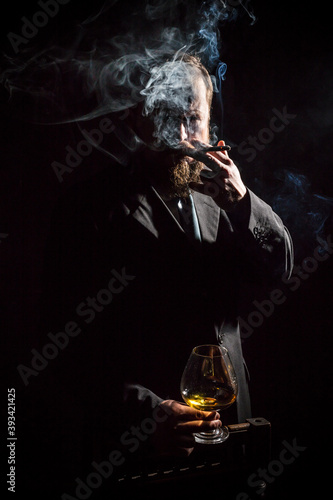 Solid confident bearded man in suit with glass of whisky and cigar