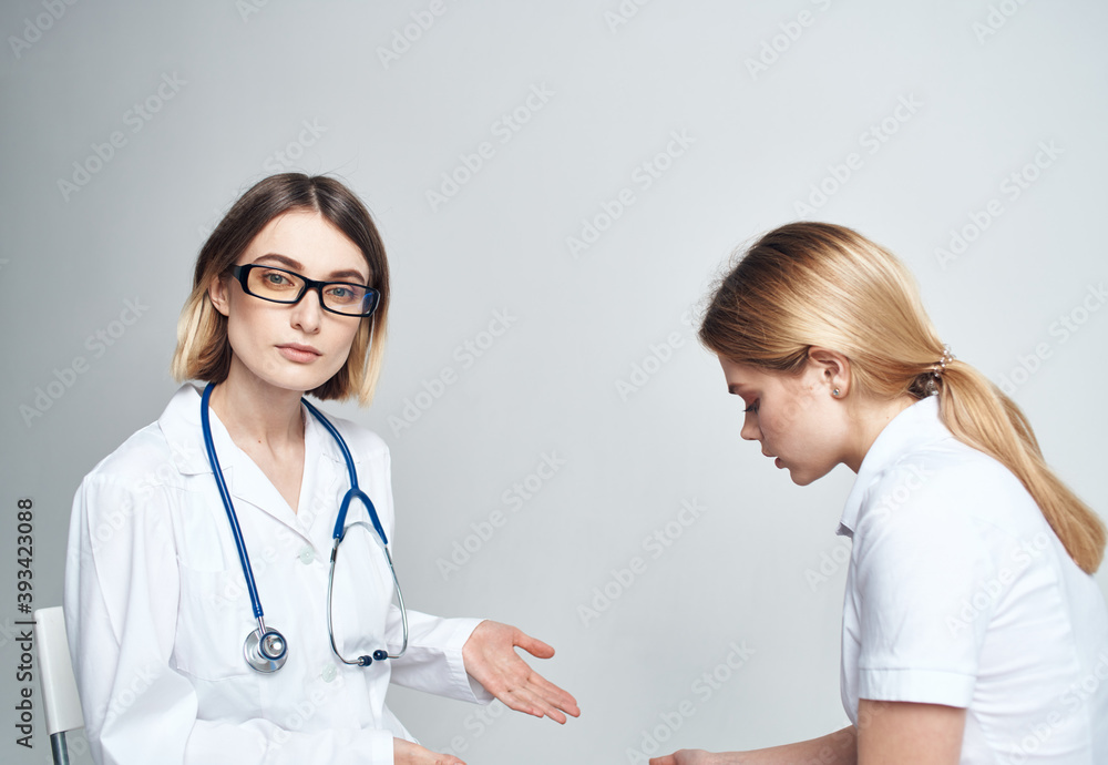 Doctor sits on a chair and woman patient indoors on a light background cropped view Doctor sits on a chair and woman patient indoors on a light background cropped view