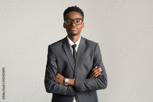 handsome young african man in suit on gray background wearing glasses