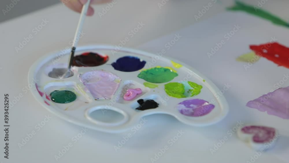 Brush picks watercolor paints on palette Brush picks watercolor paints on palette