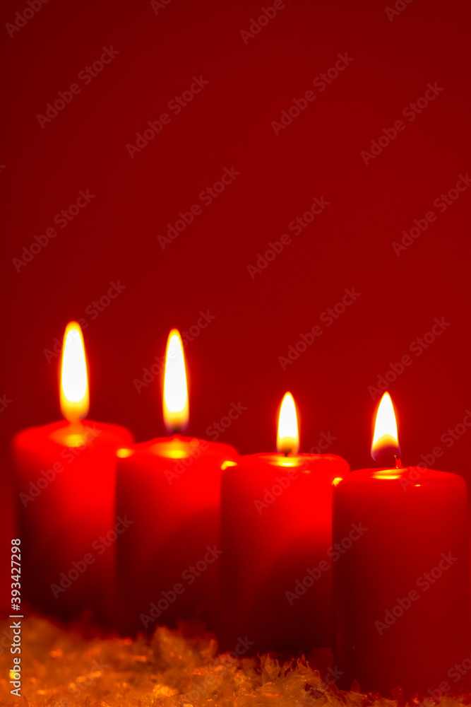 Four burning candles on snow dark red background Four burning candles on snow dark red background