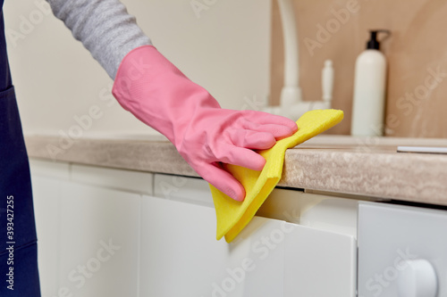 Close-up of a woman's hand in a rubber glove with microfiber. A woman is cleaning the kitchen. Without a face. Home routine. Professional cleaning.