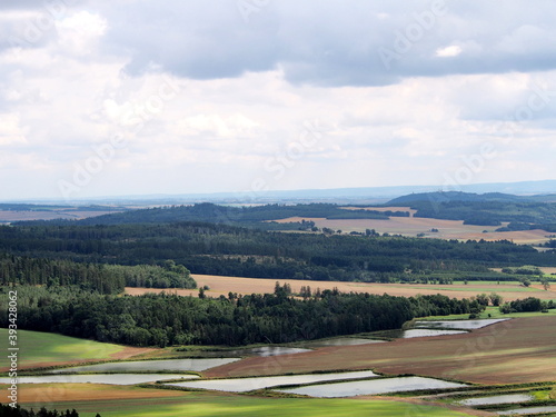 view of square water retention reservoirs in fields, cascades in agricultural landscape, forests and hills in background, summer