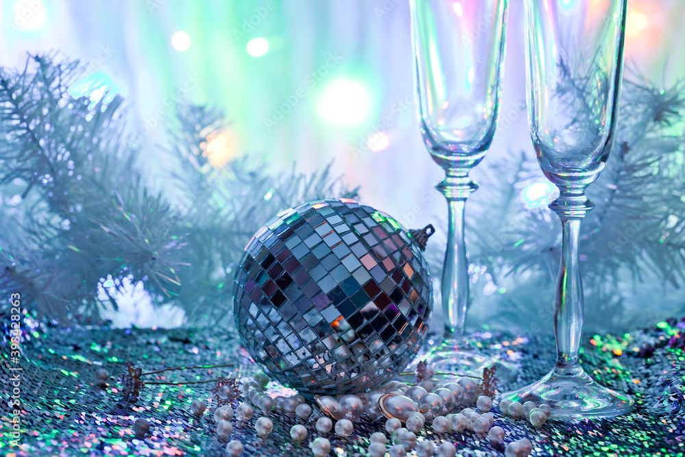 Fototapeta premium Whineglasses with disco ball and pearl beads on a colorful background. New year celebration concept.