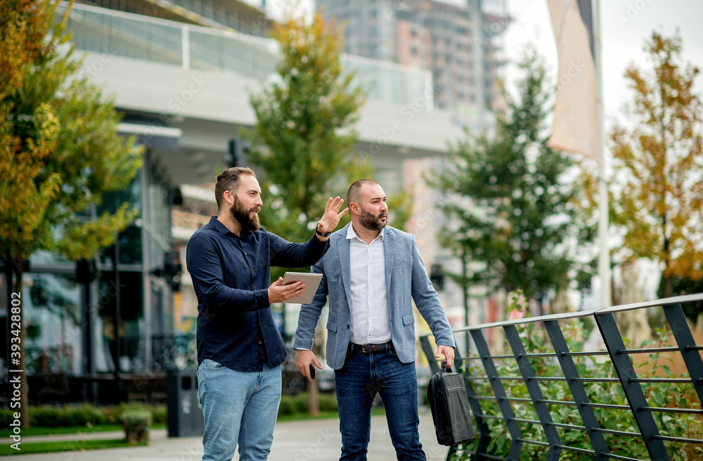 Young businessmen standing with tablet and discussing about plans for the future of the company Young businessmen standing with tablet and discussing about plans for the future of the company
