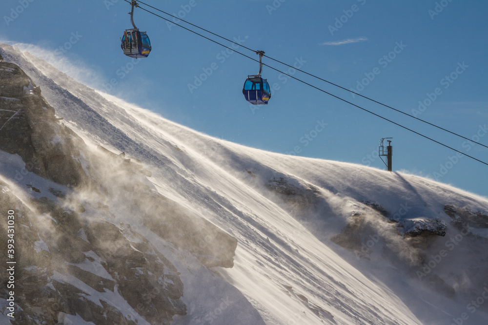 Ski lifts in the winter sports region Bad Gastein, Austrian Alps. Snowstorm on a sunny day