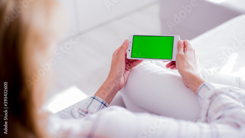 woman is relaxing on comfortable couch and using smartphone at home