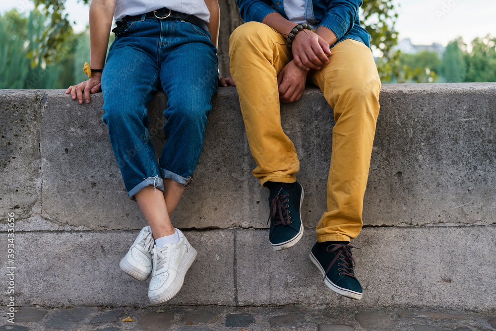 Legs of a couple sitting on a wall Legs of a couple sitting on a wall