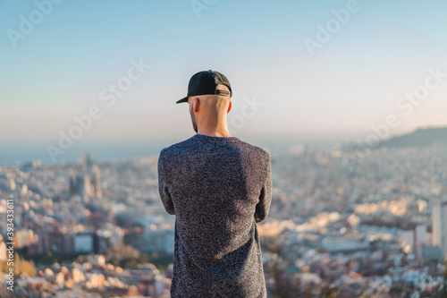 Spain, Barcelona, young man standing on a hill overlooking the city photo