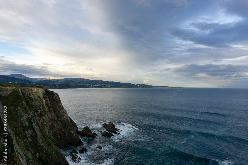 jagged and rocky ocean coast with cliffs and a rainbow